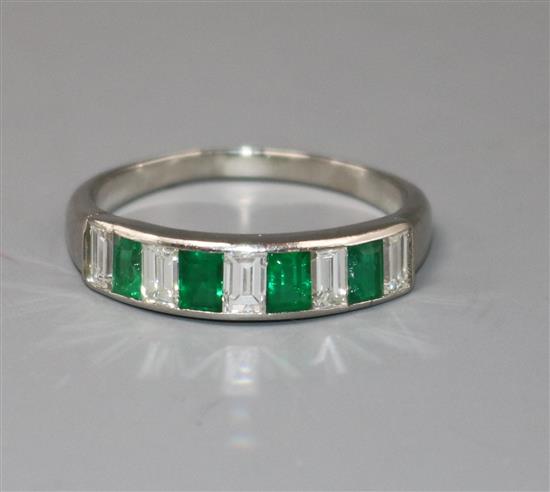 A modern white metal and nine stone emerald and diamond set half eternity ring, size W.